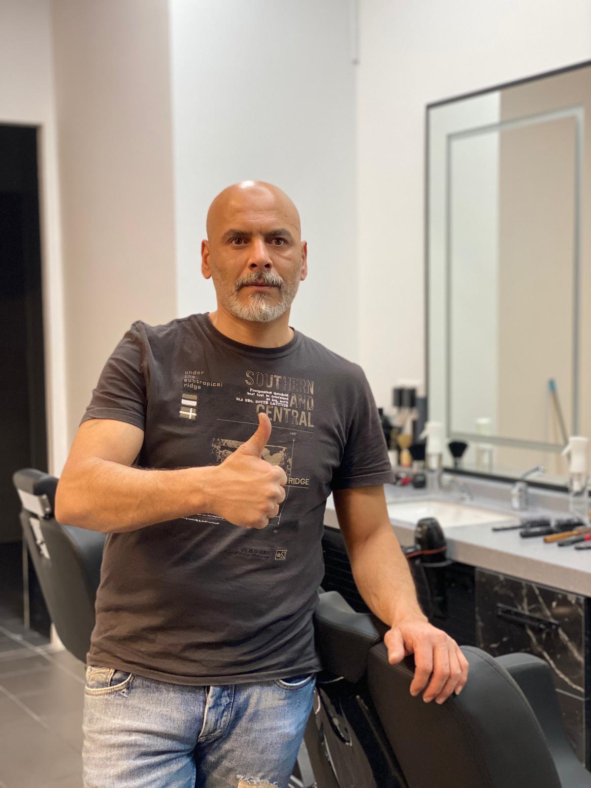 Barber in de salon met duim omhoog.